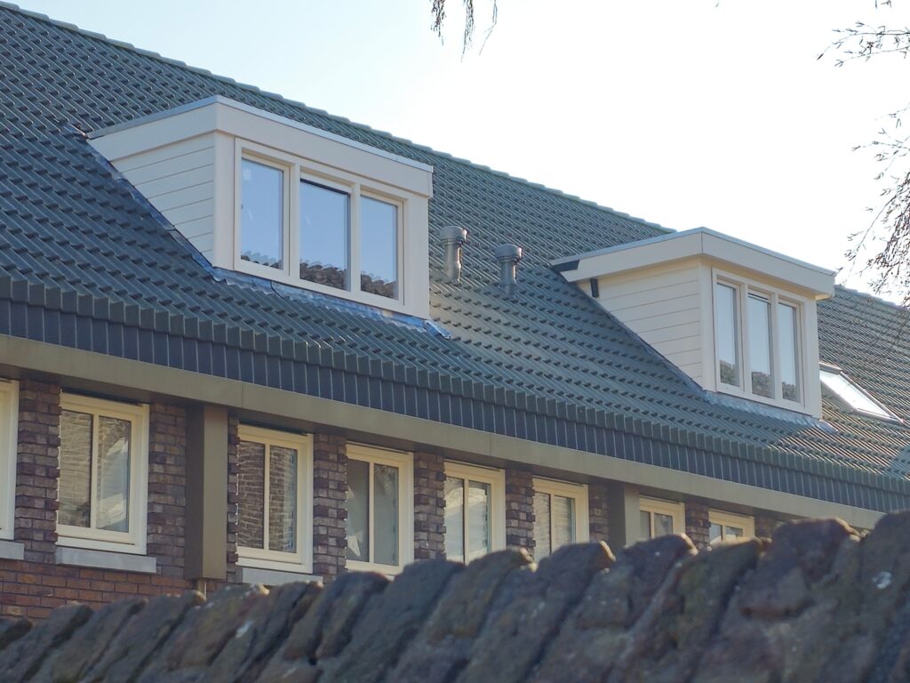 Twee vergunde crèmewitte dakkapellen aan de voorzijde van naastgelegen woningen in Moerwijk-Zuid, Den Haag